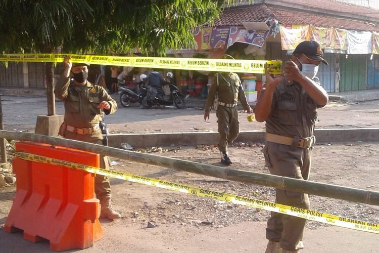 Petugas Satpol PP Kabupten Tegal, Jumat (18/9/2020) sore memasang garis penutupan Pasar Trayeman Slawi yang diberlakukan mulai Sabtu-Senin (19-21/9/2020) menyusul dua pedagang terkonfirmasi positif Covid-19.  (Foto: Dok. Humas Pemkab. Tegal)