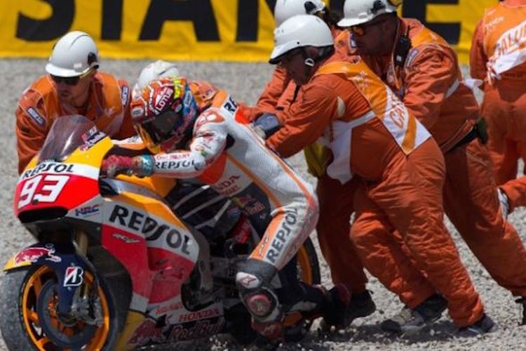 Pebalap Repsol Honda asal Spanyol, Marc Marquez, mencoba menghidupkan motornya dengan bantuan marshal setelah terjatuh pada balapan GP Catalunya di Sirkuit de Barcelona, Minggu 914/6/2015).