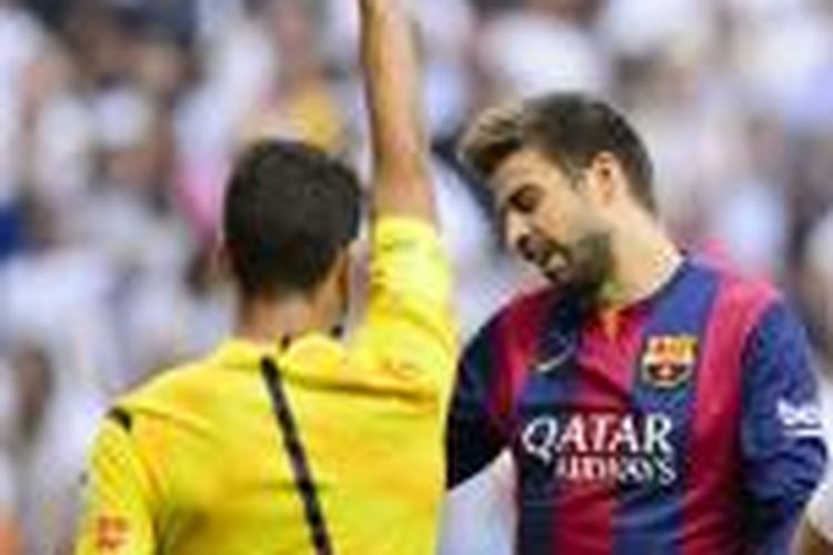 Bek Barcelona Gerard Pique mendapatkan kartu kuning dari wasti Jesus Gil Manzano, karena melakukan handsball di kotak penalti, pada pertandingan Primera Division melawan Real Madrid, di Santiago Bernabeu, Sabtu (25/10/2014).