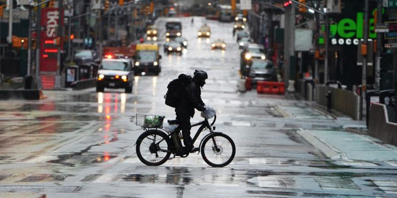 Pengantar barang mengendarai sepedanya menyeberangi 7th Avenue di kawasan Times Square yang kosong akibat meluasnya penularan virus COVID-19, di wilayah Manhattan, New York, Amerika Serikat, Senin (23/3/2020).