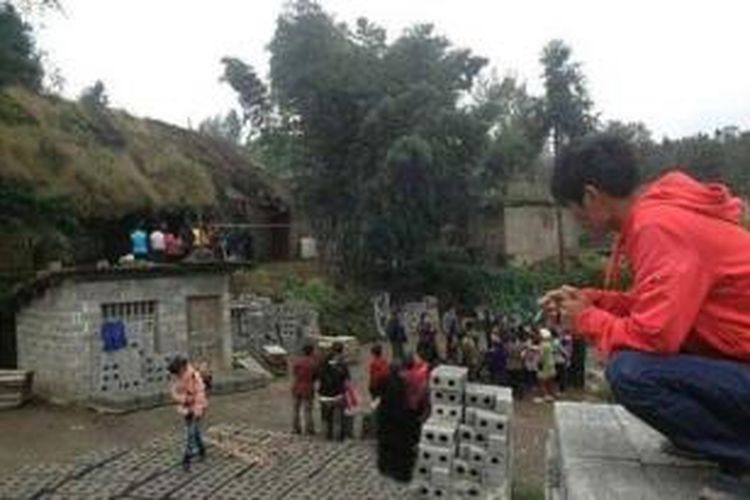 Warga desa Zhenxiong, China berkerumun di depan kediaman Tang Minghua yang membunuh anak kandungnya sendiri hanya karena bocah itu mengompol.