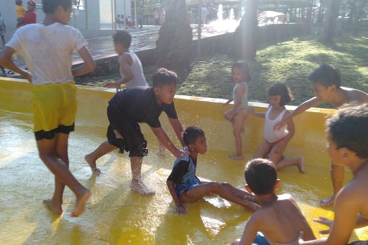 sekumpulan anak bermain prosotan di jalur skateboard yang basah di Taman Puring, Kebayoran Baru, Jakarta Selatan, Selasa (14/1/2020)