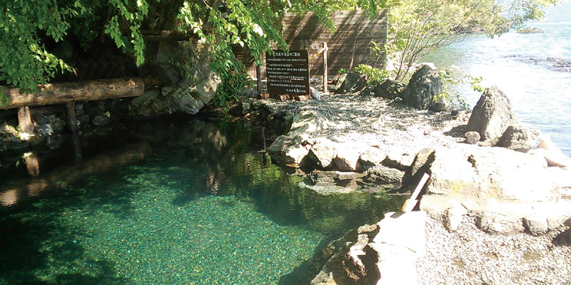 Onsen (permandian air panas) yang hanya berbatasan batu dengan Danau Shikotsu di Jepang.