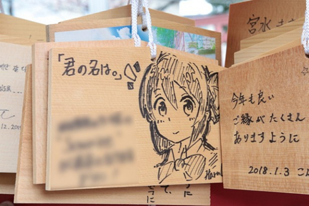 Gambar Mitsuha, salah satu tokoh utama dalam film Your Name, pada papan ema 
