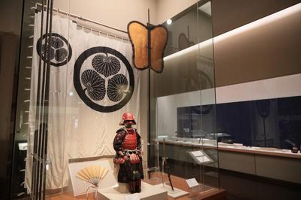 “Gusoku Samurai Armor” yang dibuat dan dipakai oleh tuan pertama, Yoshinao. Di belakangnya terdapat gambar lambang keluarga Tokugawa, yaitu daun mitsuba (asarum caulescens) pada lembaran kain dan bendera perang