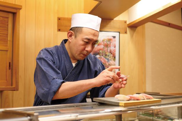 Koki sushi dengan hati-hati menyiapkan setiap hidangan di restoran.