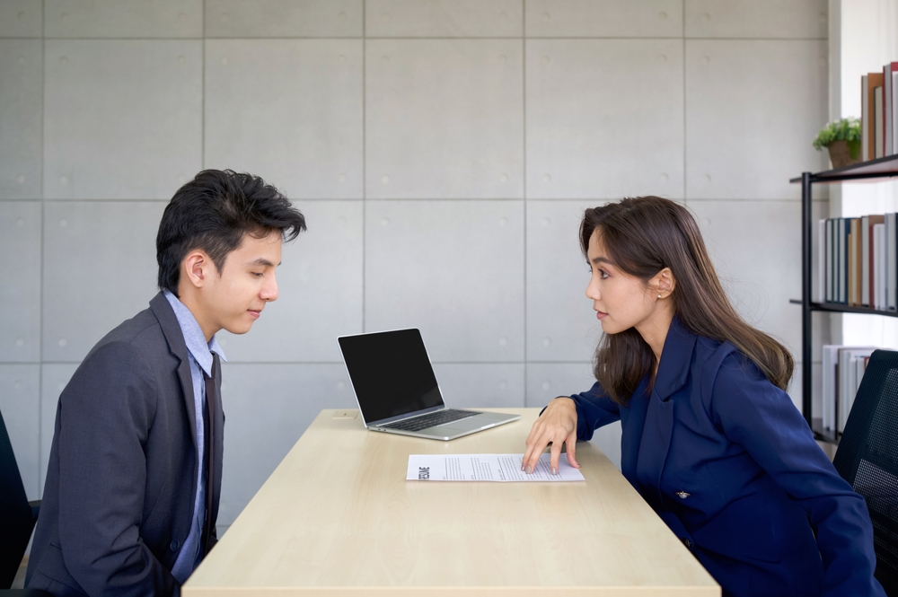 Young asian manager in blue suit asks a candidates profile during an interview. The atmosphere of job interview in the modern office.