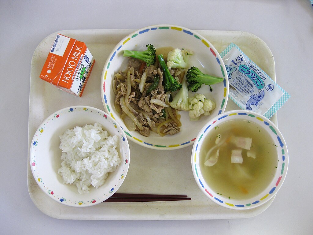 Makan siang sekolah ini berisi nasi, sup miso, sekotak susu, sebungkus ikan kering kecil, dan tumis daging dengan sayuran. Foto ini diambil di sebuah sekolah dasar negeri di Jepang.