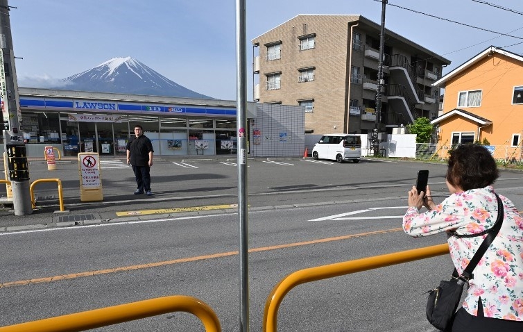 Turis mengambil foto di depan Lawson dengan pemandangan Gunung Fuji pada Mei 2024.