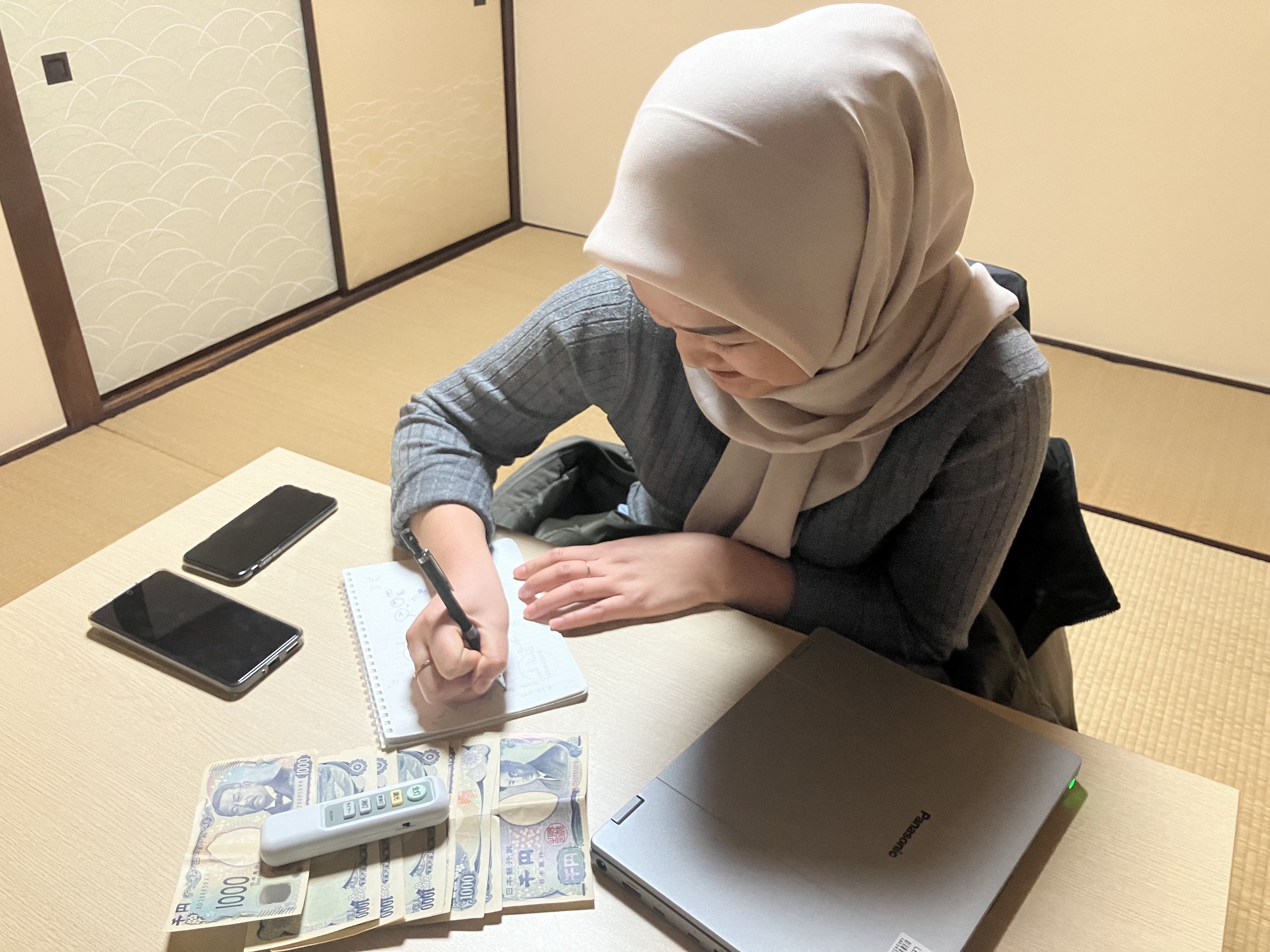 Ifah, pekerja SSW di Jepang sedang mencatat dan membagi keuangan.