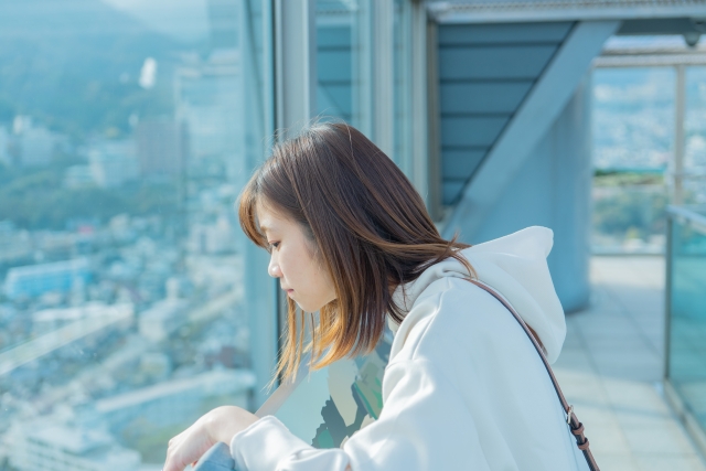 Seorang perempuan memakai jaket capuchon sedang menikmati pemandangan.