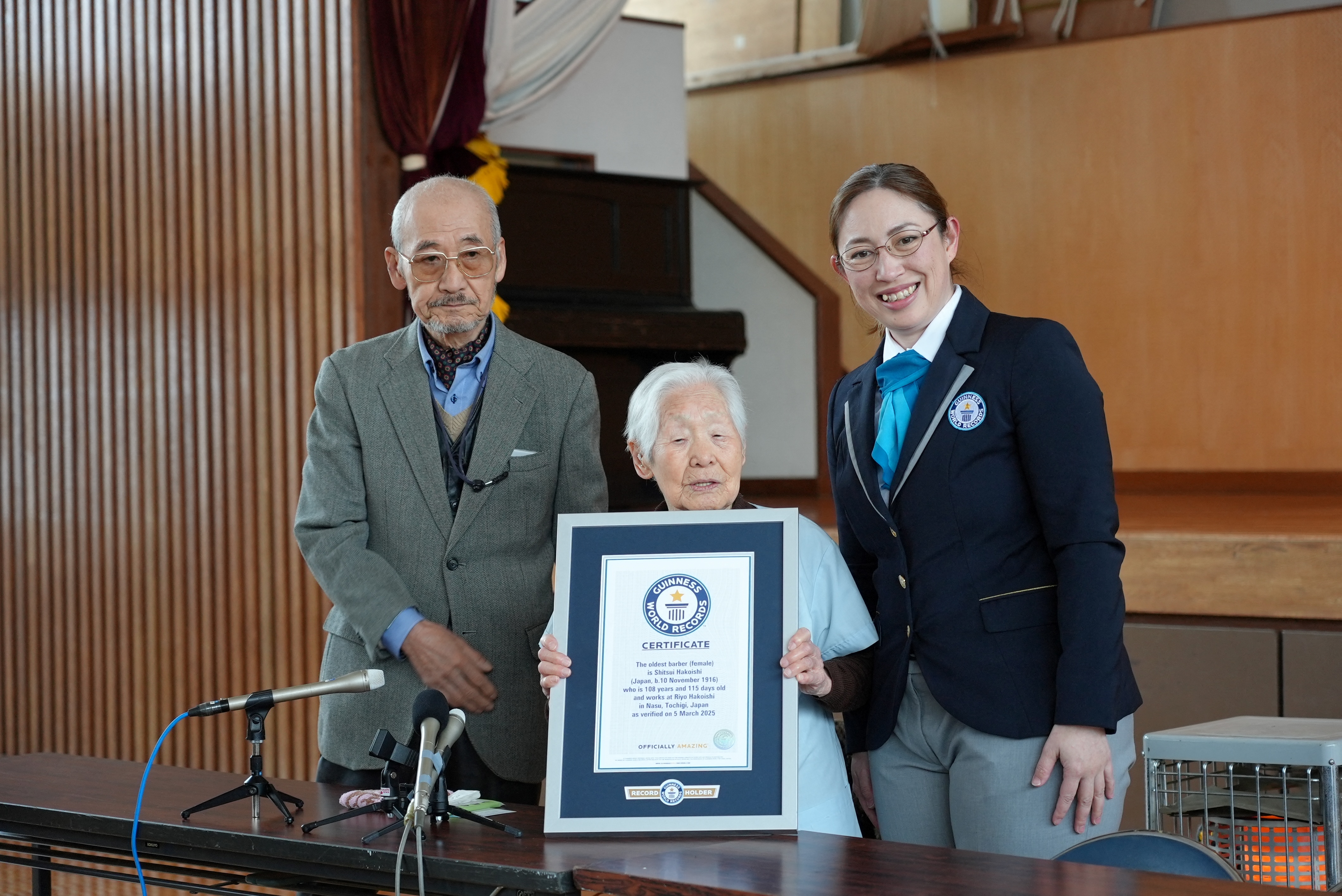 Shitsui Hakoishi, tukang cukur tertua di dunia dari Jepang berusia 108 tahun. Ia berfoto bersama putra tertuanya, Hidemasa, dan staf Guinness World Records di Kota Nakagawa, Prefektur Tochigi. (Foto diambil pada 5/3/2025)