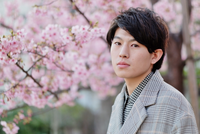 Seorang pria mengenakan outfit musim semi sedang menikmati keindahan bunga sakura.
