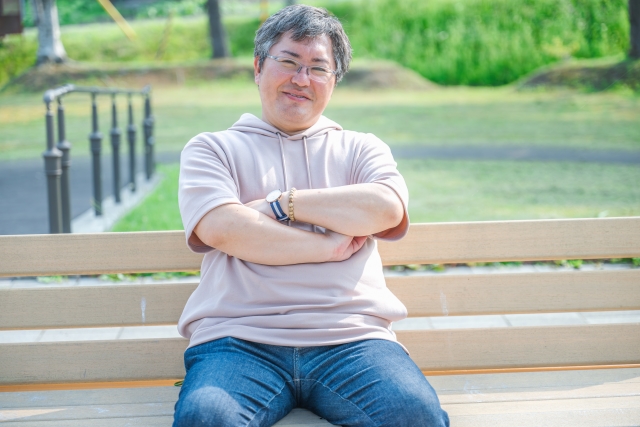 Seorang pria mengenakan outfit sweater dengan capuchon.