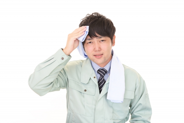 Seorang pria mengenakan outfit jaket sedang menyeka keringat di wajahnya dengan handuk.