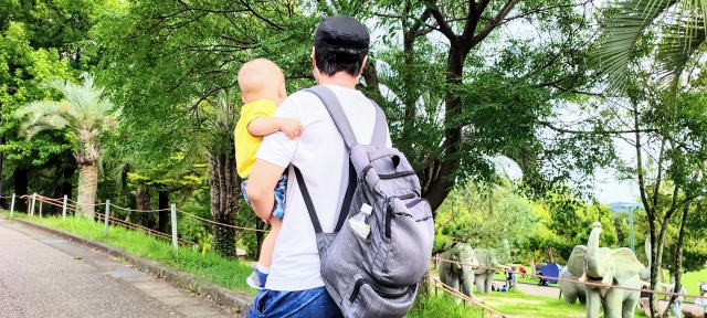 Seorang pria mengenakan outfit kaos sedang menggendong anak.