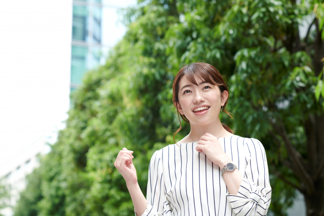 Seorang wanita mengenakan outfit blus motif salur.