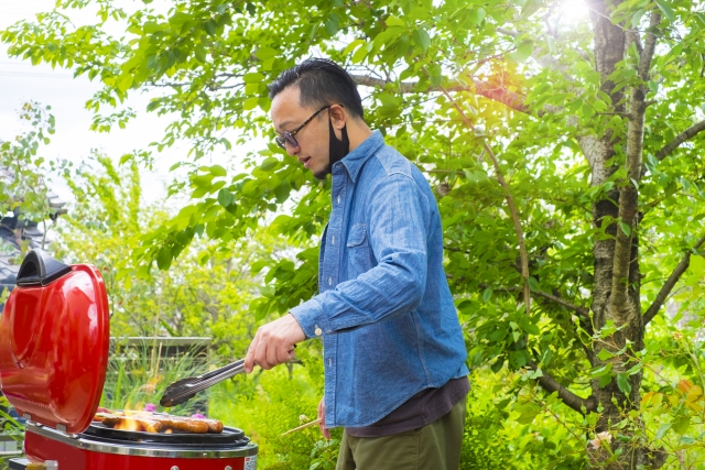 Seorang pria mengenakan outfit kemeja jeans sedang barbeque.
