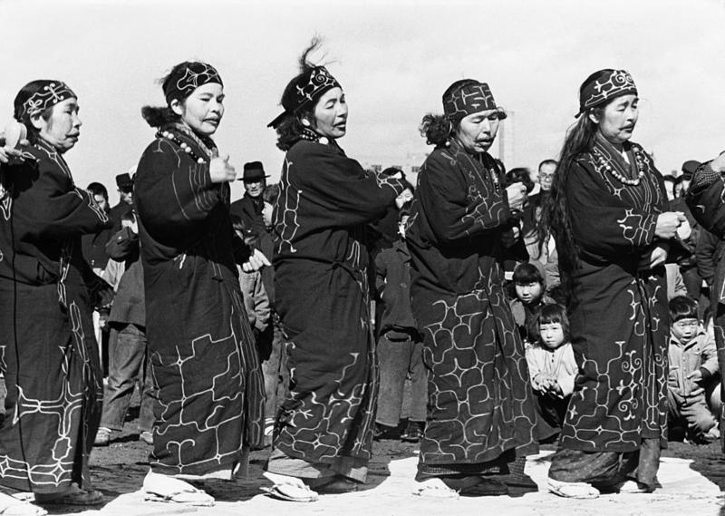 Sekelompok perempuan Ainu menampilkan tarian tradisional, sekitar tahun 1950. Orang-orang Ainu tidak memiliki bahasa tertulis, sedangkan bahasa lisan mereka diyakini tidak berhubungan dengan bahasa lain yang dikenal luas.
