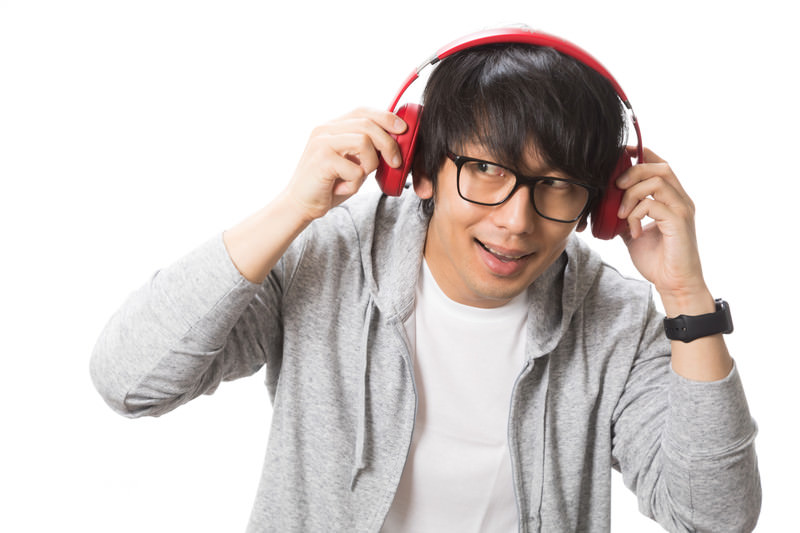 Ilustrasi orang Jepang mendengarkan lagu menggunakan headphone.