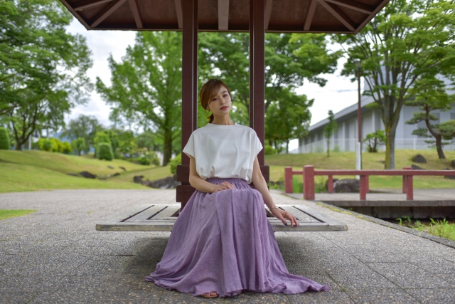 Seorang wanita memakai outfit blus dan rok panjang sedang bersantai.