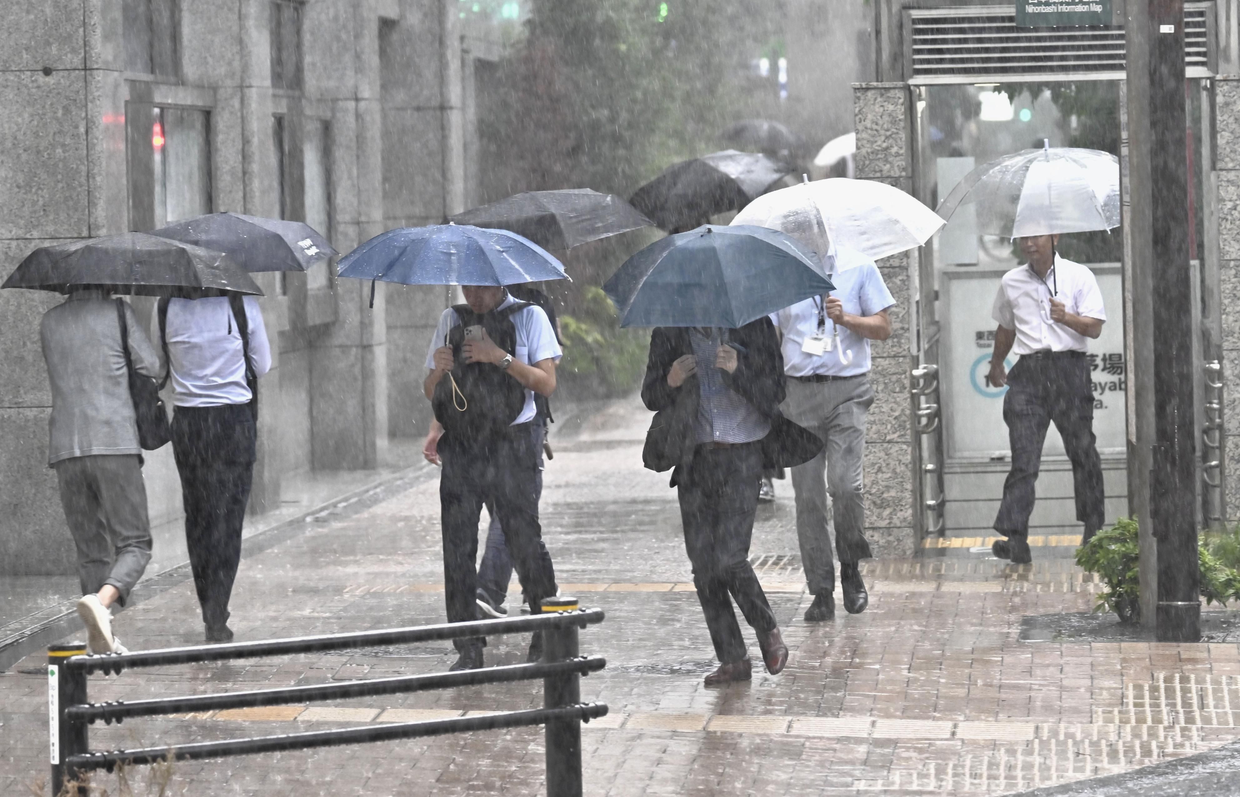 Orang-orang berjalan dengan payung di tengah hujan lebat di pusat Tokyo pada 11 September 2025.