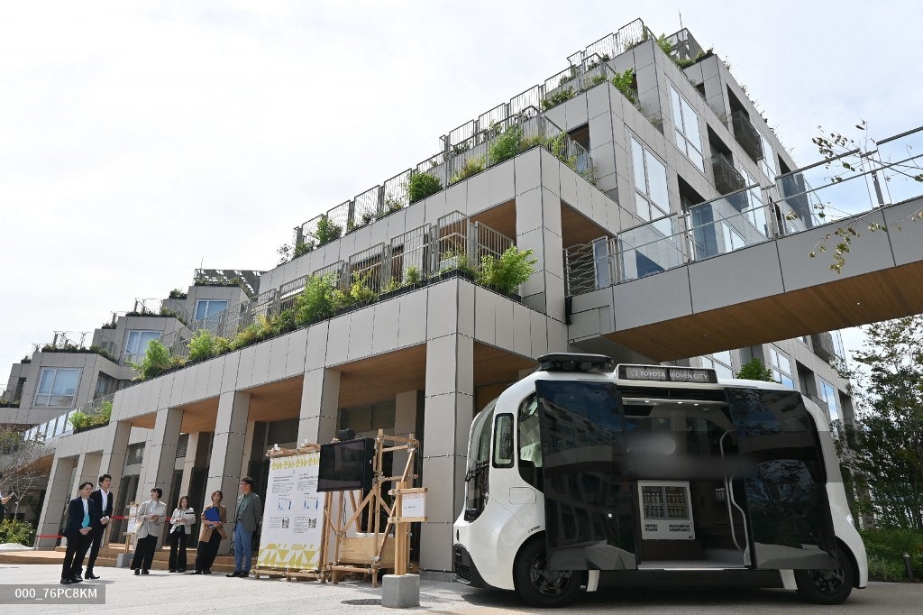 Halaman kompleks Woven City milik Toyota Motor Corporation dan kendaraan listrik tanpa pengemudi (EV) e-Palette (kanan) tampak di Kota Susono, Prefektur Shizuoka, (25/9/2025). Toyota meresmikan desa berteknologi tinggi baru di Jepang, sebagai proyek eksperimental untuk menguji kendaraan otonom dan berbagai inovasi futuristik.