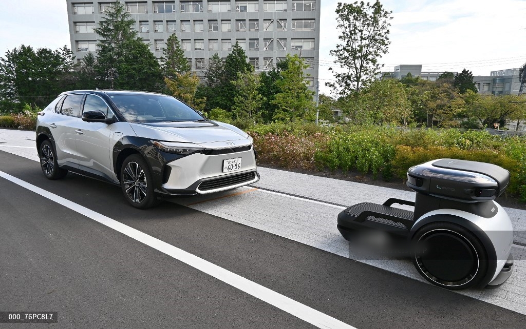 Sebuah robot otonom (kanan) memandu dan mengangkut mobil bersama di dalam kawasan ‘Woven City’ milik Toyota Motor Corporation di Kota Susono, Prefektur Shizuoka, (25/9/2025). Produsen mobil terlaris Toyota meresmikan desa berteknologi tinggi baru di Jepang, sebagai proyek eksperimental untuk menguji kendaraan otonom dan berbagai inovasi futuristik.