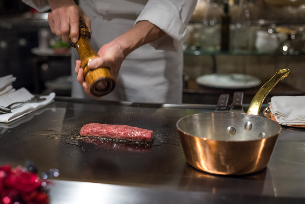 Ilustrasi koki sedang mengolah daging sapi wagyu di restoran fine dining Jepang. 