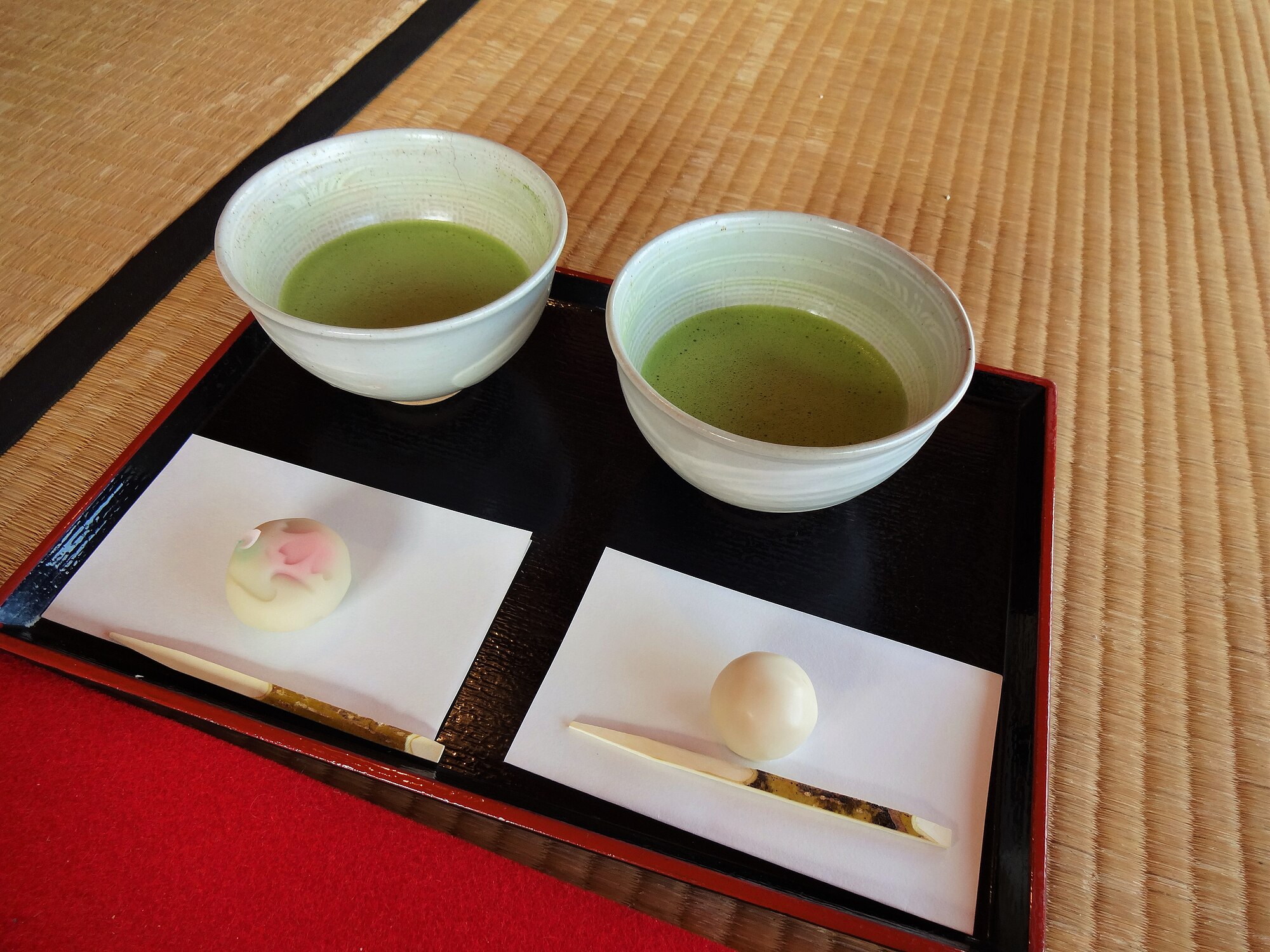 Nampan teh Jepang dengan dua cangkir matcha beserta beberapa kue manis selama upacara teh di Taman Hamarikyu, Tokyo, Jepang.
