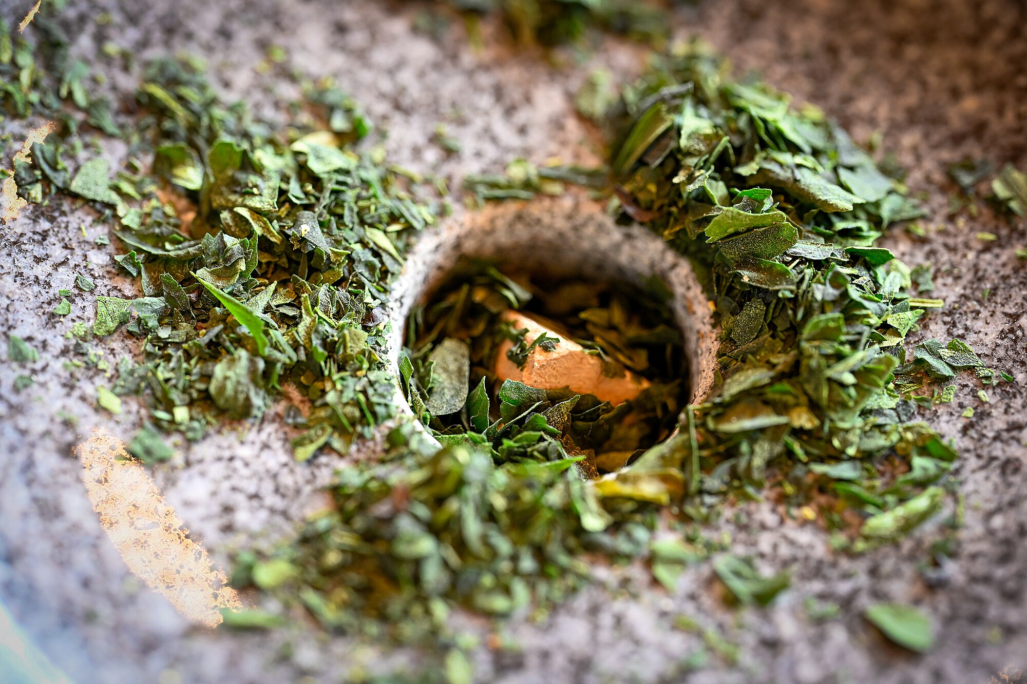 Foto makro daun Tencha yang digiling menggunakan batu granit tradisional di pabrik penggilingan untuk produksi Matcha di Uji, Kyoto, Jepang.
