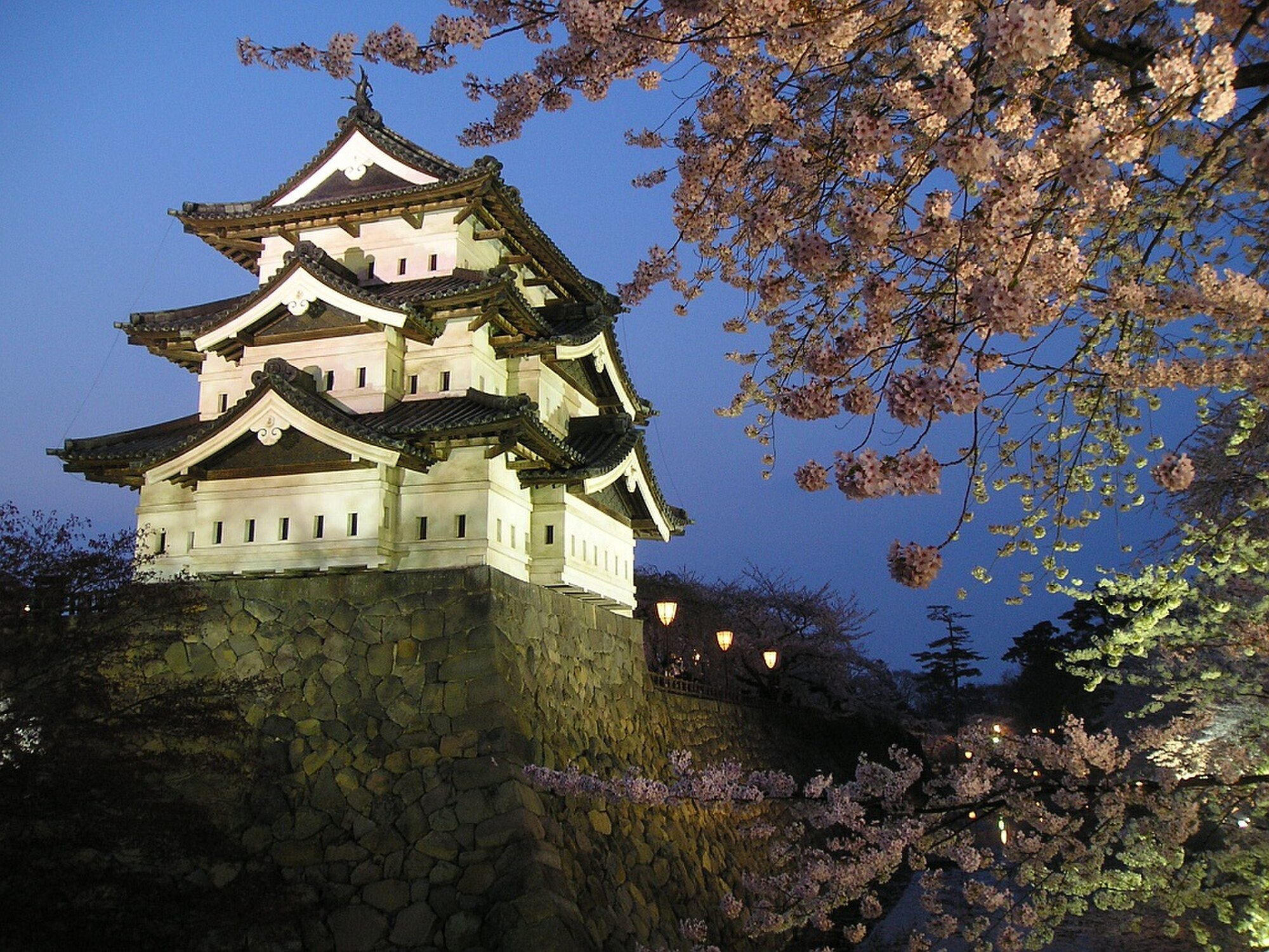 Menara Hirosaki Castle di Kota Hirosaki, Prefektur Aomori, dan penerangan bunga sakura pada malam hari (difoto di dalam Taman Hirosaki selama periode Festival Bunga Sakura Hirosaki).