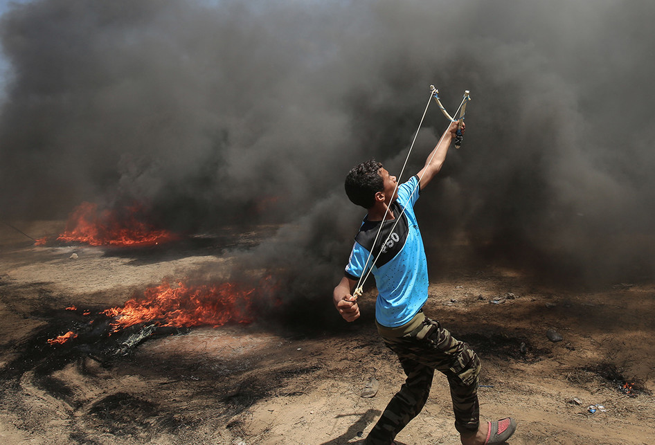 Seorang warga Palestina menyerang dengan ketapel saat terjadi bentrokan dengan pasukan Israel di dekat perbatasan antara jalur Gaza dan Israel, di sebelah timur Kota Gaza, Senin (14/5/2018). Otoritas Palestina menyebut pasukan Israel telah menewaskan 55 orang dan melukai 2.700 orang dalam aksi protes dan bentrokan menentang pembukaan Kedutaan Besar Amerika Serikat di Yerusalem.. (AFP PHOTO/SAID KHATIB)