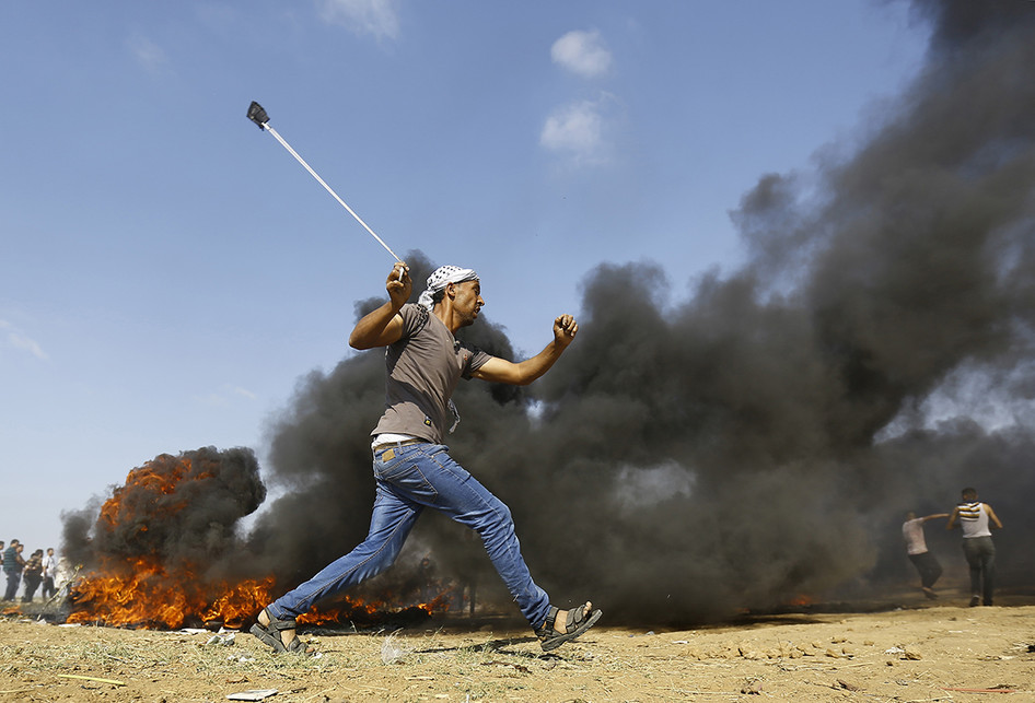 Seorang warga Palestina berupaya menyerang dengan batu saat terjadi bentrokan dengan pasukan Israel di dekat perbatasan antara jalur Gaza dan Israel, di sebelah timur Kota Gaza, Senin (14/5/2018). Otoritas Palestina menyebut pasukan Israel telah menewaskan 55 orang dan melukai 2.700 orang dalam aksi protes dan bentrokan menentang pembukaan Kedutaan Besar Amerika Serikat di Yerusalem.. (AFP PHOTO/MOHAMMED ABED)