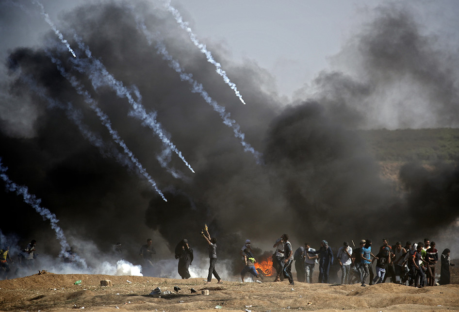 Warga Palestina menjauh usai dilempar gas air mata saat terjadi bentrokan dengan pasukan Israel di dekat perbatasan antara jalur Gaza dan Israel, di sebelah timur Kota Gaza, Senin (14/5/2018). Otoritas Palestina menyebut pasukan Israel telah menewaskan 55 orang dan melukai 2.700 orang dalam aksi protes dan bentrokan menentang pembukaan Kedutaan Besar Amerika Serikat di Yerusalem.. 