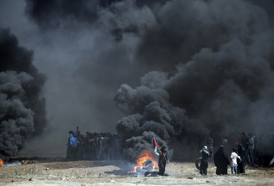 Warga Palestina membakar ban saat terjadi bentrokan dengan pasukan Israel di dekat perbatasan antara jalur Gaza dan Israel, di sebelah timur Kota Gaza, Senin (14/5/2018). Otoritas Palestina menyebut pasukan Israel telah menewaskan 55 orang dan melukai 2.700 orang dalam aksi protes dan bentrokan menentang pembukaan Kedutaan Besar Amerika Serikat di Yerusalem.. (AFP PHOTO/THOMAS COEX)