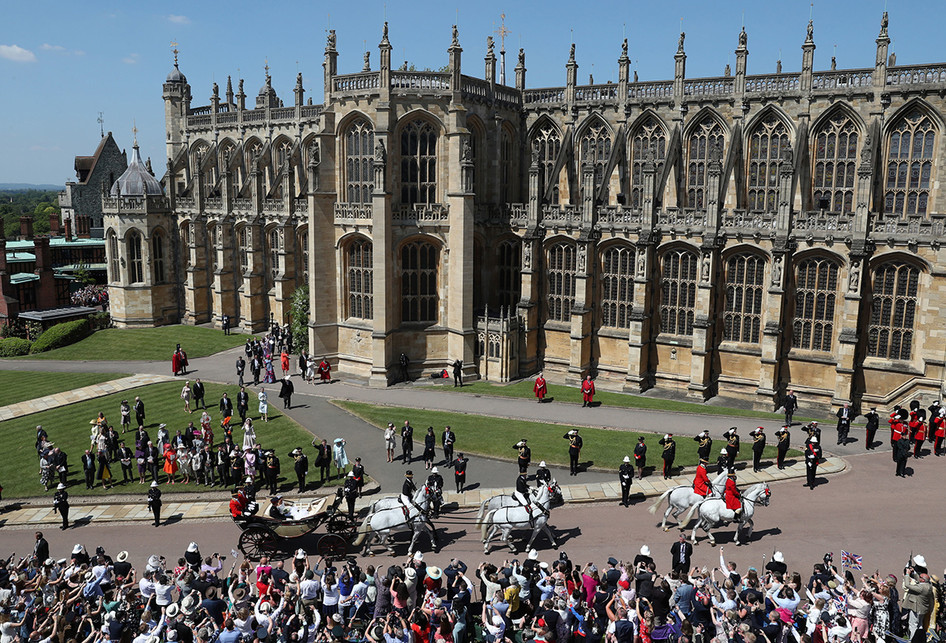 Pangeran Harry dan Meghan Markle menaiki kereta kencana Ascot Landau menjelang acara pemberkatan pernikahan di Windsor, Inggris, Sabtu (19/5/2018). Sebanyak 600 tamu undangan menghadiri jamuan makan siang dan makan malam pada acara resepsi, ditambah 2.640 tamu dari warga biasa yang akan menimati teh dan kudapan di Istana Windsor.. (AFP PHOTO/POOL/ANDREW MILLIGAN)